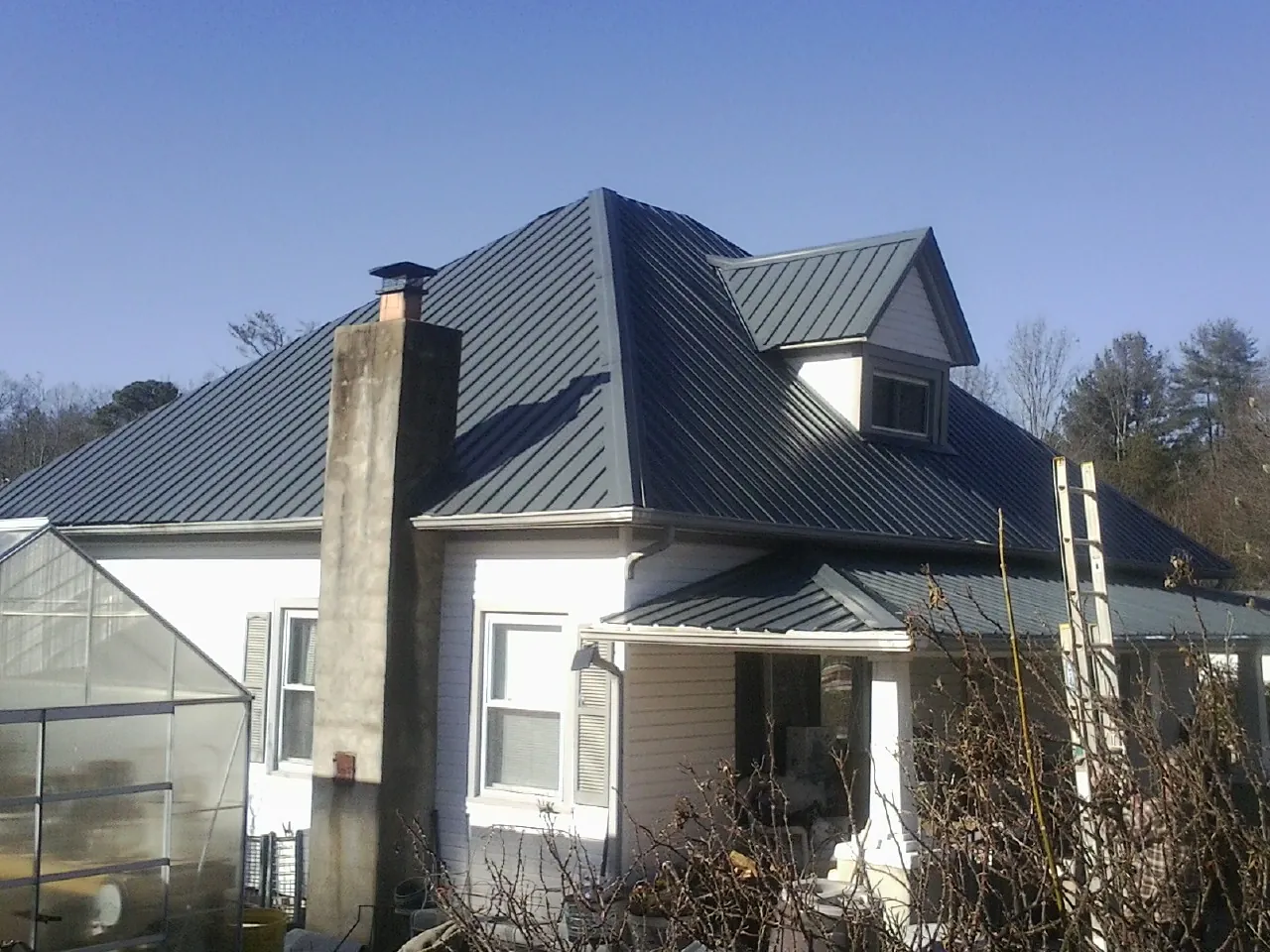 Dark blue standing seam metal roof on a white farmhouse with dormer — Slate & Tile Roof Repair by Roofing Brothers in El Cerrito