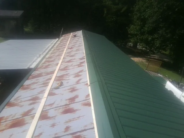 Old rusted panels beside newly installed green metal roofing — Wind Damage Roof Repair by Roofing Brothers in El Cerrito