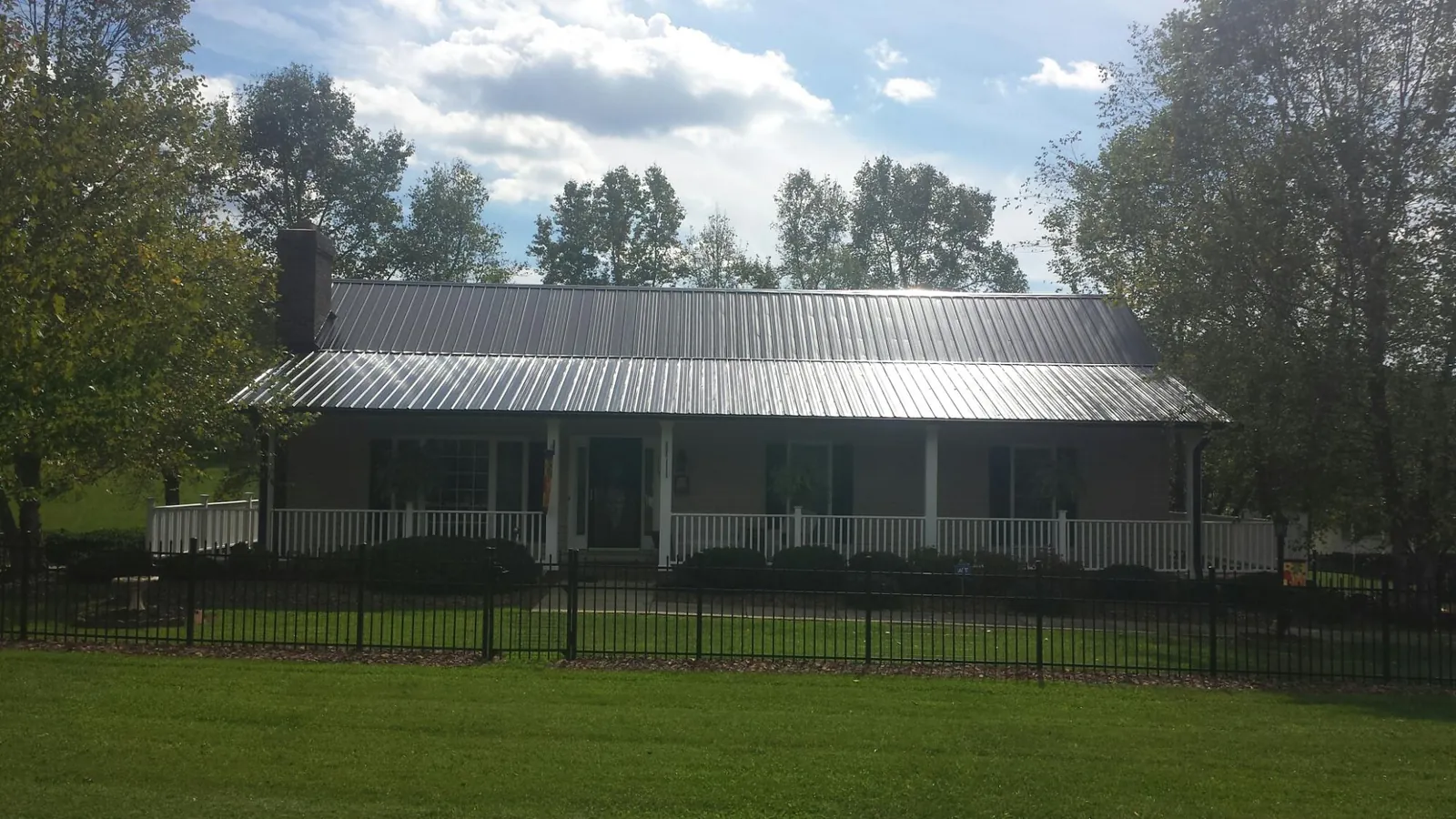 Gray metal roof on a brick ranch with a full width front porch — Gutter Guard Installation work by our crew in El Cerrito