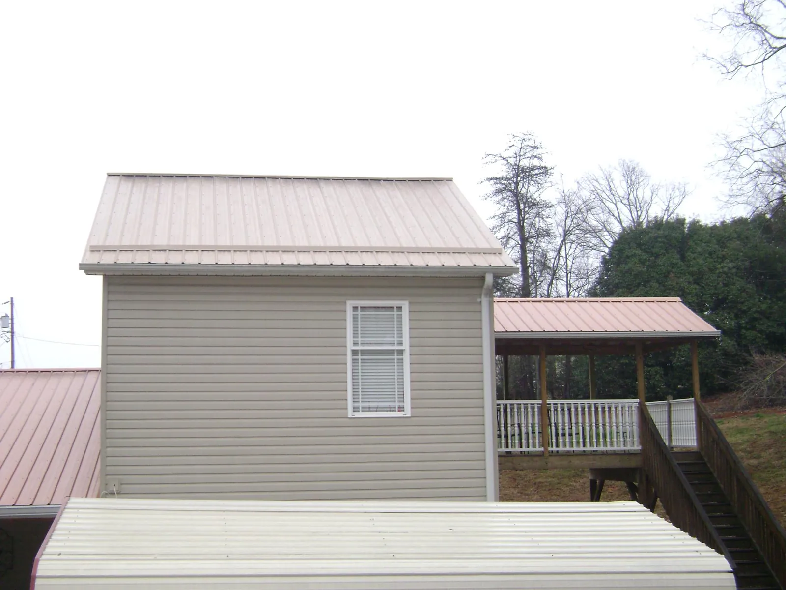 Tan metal roofs on a two story addition and attached porch, from a Roof Replacement job in El Cerrito