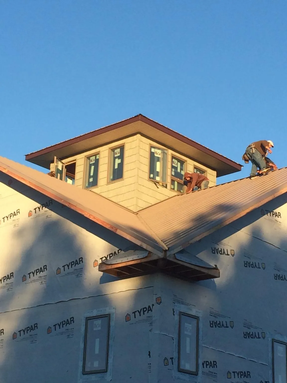 Roofers working around a rooftop cupola on a new metal roof at sunset — Roof Waterproofing in El Cerrito by Roofing Brothers